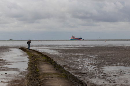 Beautiful North Sea coast of Cuxhaven in Germany. Overcast sky with clouds over the sea at low tide.のeditorial素材