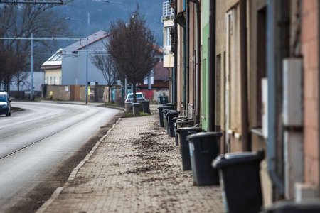 Part of the street, roads and houses. There are plastic garbage cans near the houses. The background is blurred by the technique of photography.の写真素材