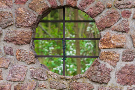 The wall in which the round hole is like a window and the window has a lattice. Behind the bars is...