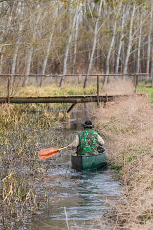 The paddler floats on a canoe along a small overgrown river.の写真素材