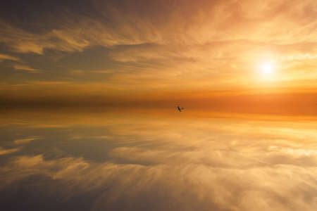 A small plane flies in the air. In the background is a beautiful colorful sky with the setting sun.の写真素材