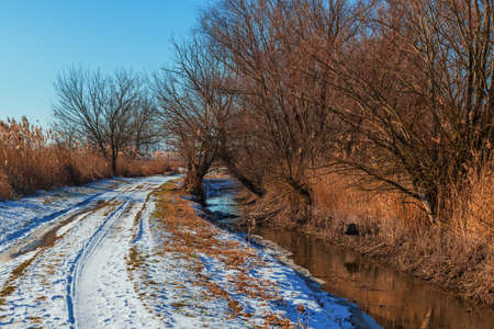 Winter landscape. Road on which there is white snow. A stream flows along the road.の写真素材