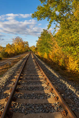 Old monorail train by the Hlohovec pond. There are trees around the track. The sky is blue with white clouds. The sun shines on the landscape.の写真素材
