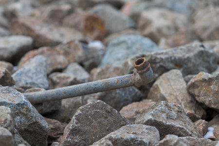 An old rusty metal pipe lies in the stones.の写真素材
