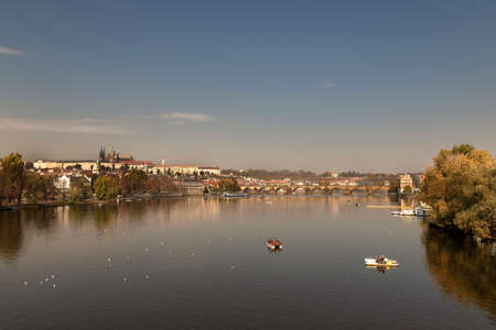View of the Charles Bridge and the Vltava River on a sunny day in the city of Prague with a boat on...