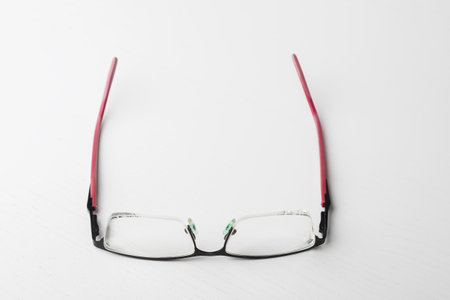 Unfolded eyeglasses lie on a white table.