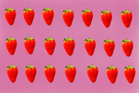 Red strawberries lined up in a row on a pink background.