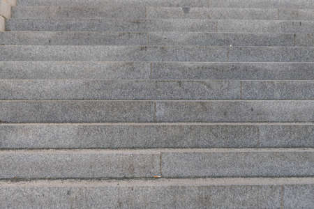 Granite stairs going up. There is trash on the stairs.
