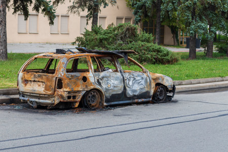 An old rusty car that burned down. A burned-out car stands on the side of the road.の写真素材