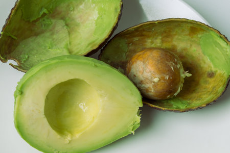 Avocado cut in half on a white plate. A seed in an avocado.