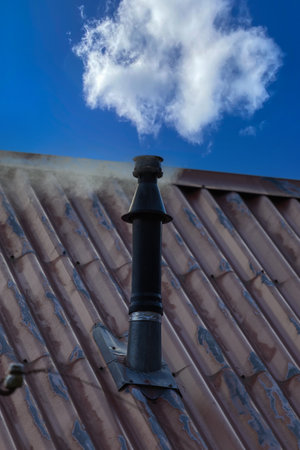 An old tin roof with a chimney that smokes from.