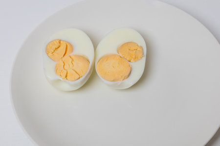 Half chicken egg on a white plate. An egg has two yolks.