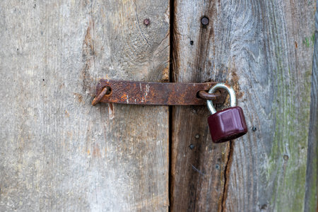Black padlock on the door of a wooden stand. Locked window with a padlock.の写真素材