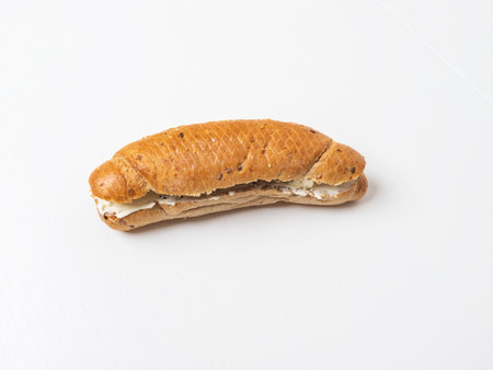 A healthy cereal roll spread with cheese for a snack. The roll is on a white background.の写真素材