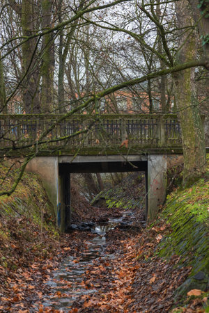 A dry drainage canal bed with a bridge in the background.の写真素材