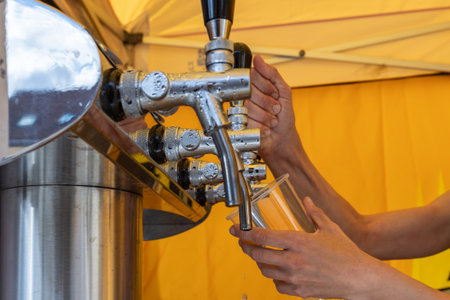 Beer tap stand - tap. Hands holding a cup and tapping beer
