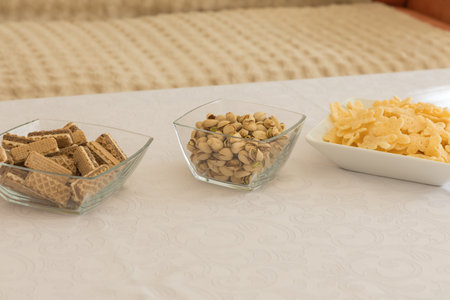 Three bowls with different types of snacks arranged in a row on a white table.の写真素材