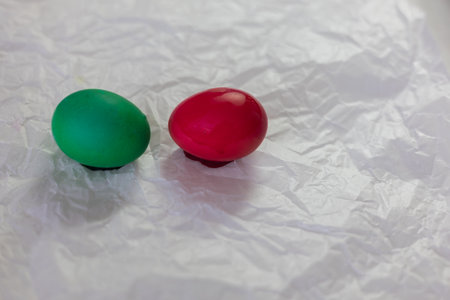 Brightly colored Easter eggs â various colors - green, yellow, red, blue â arranged on crumpled white paper. The eggs are smooth and shiny, ready for decoration or display at Easter.の写真素材