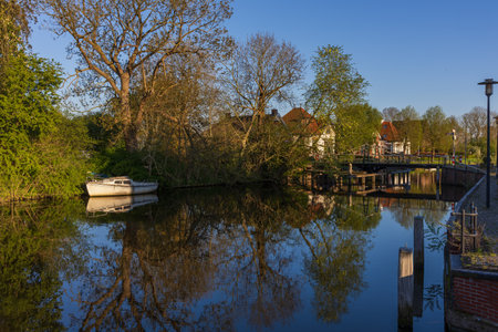 Canal scene in Bedum with a moored boat, red-roofed houses, and a wooden bridge. A perfect...