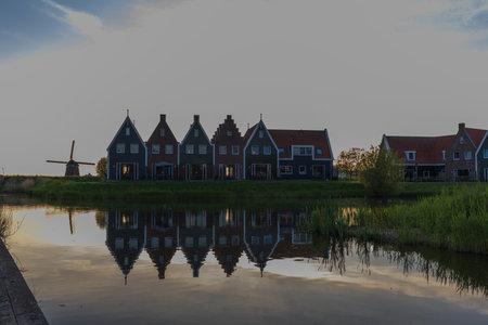 Silhouettes of houses and a windmill at sunset in Volendam. Magical reflection on the canal surface in North Holland province.の写真素材