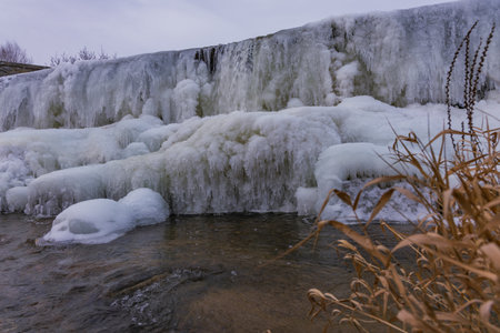 Spectacular ice formations and massive icicles on the CvrÄovice dam on the Jihlava River. The photos capture the harsh winter beauty of the Czech landscape, featuring the contrast between frozen ice cascades and cold flowing water during a winter freezeの写真素材