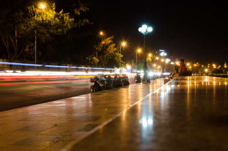 People watch as motorcycle with trailing lights at nightのeditorial素材