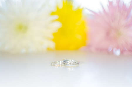 engagement and wedding ring on white flower background made of shiny whitegold and diamondsの写真素材