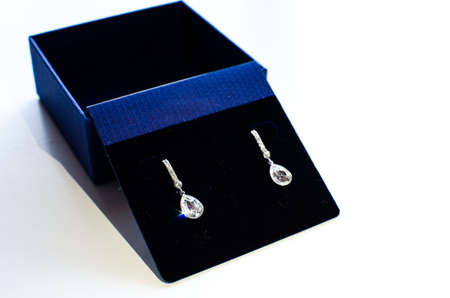 a pair of shiny, brilliant earrings made of crystal, diamond and white gold in a blue luxury caseの写真素材