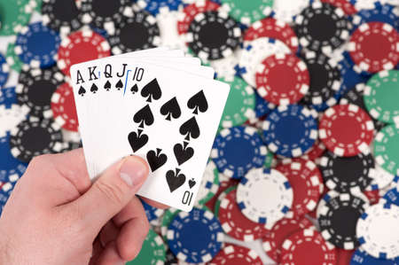 Man holding a royal flush over a pile of poker chips