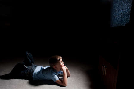 Six year old boy watching static on television in the darkの写真素材