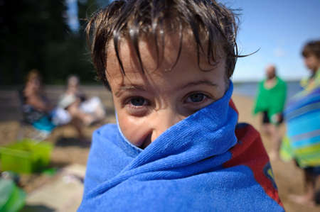 A seven year old boy drying off from swimmingの写真素材