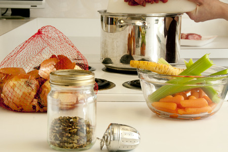 Ingredients for making soup, spices, onions, parsnips, celery,beef , pot all placed on the kitchen counter top and stove topの写真素材