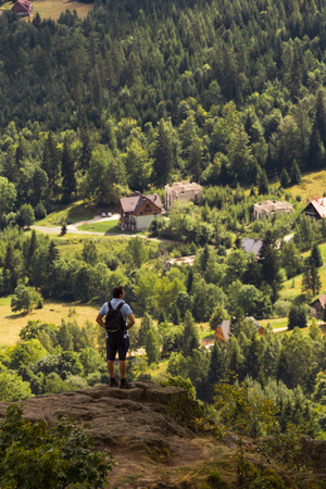 a man standing on the edge of a rock in the mountains with the view belowの写真素材