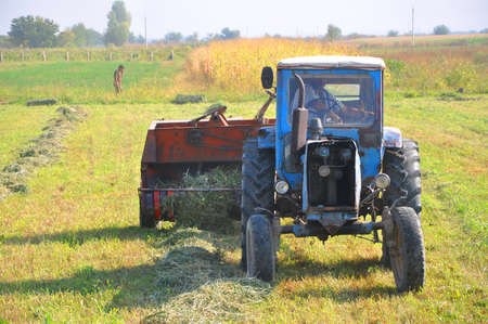 An old tractor collects hay in the field with a press-picker "Kyrgyzstan"のeditorial素材