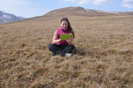A girl looks into a tablet computer near Mount Abadzesh. Caucasus Nature Reserve, Russia