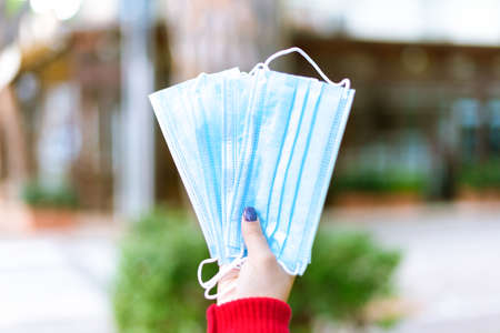 a woman hand holding lots of protective face mask outdoor after lockdown reopening.girl showing corona virus safe measures.concept about responsibility and sensibilization against covidの写真素材