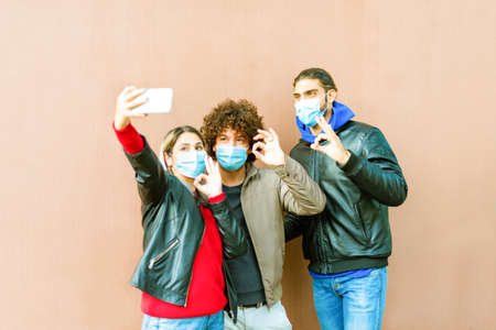 happy group of friends wearing protective face mask taking a funny selfie after the lockdown...