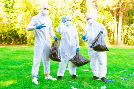 group of environmentalists volunteer collecting used gloves and protective face mask throwed away from irresponsable people after the lockdown reopening.ecologists cleaning up waste in the park.concept about sesibilization to recycle in the the new normal lifestyleの写真素材