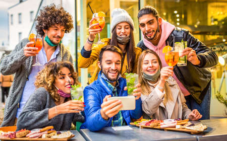 group of young millennial friends making a toast while making a selfie celebrating christmas wearing warm winter clothes.の写真素材