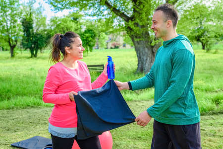 couple of a smiling personal trainer and a beautiful woman doing workout exercise outdoor in a...