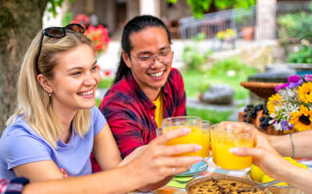 happy multiratial group of friends having breakfast brunch on a picnic table outdoor in the nature. close up portrait of a woman gathering in summer laughing in a party time. joy and lifestyle conceptの写真素材