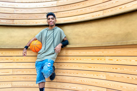 close up portrait of alternative black man hanging out chilling and smiling standing isolated against modern wood background wall. happy people holding basketball relaxing outdoors. lifestyle conceptの写真素材