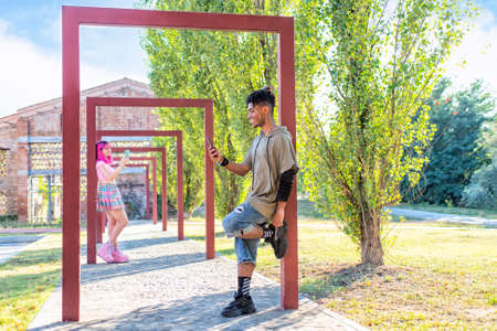 different alternatives couple hanging out together in a park holding smartphone online on social...