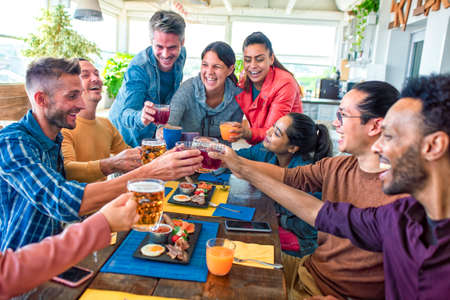 multiethnic large group of friends sitting at table in a bar restaurant having brunch. diverse people celerating salty breakfast together enjoying happy holiday. lifestyle and joy conceptの写真素材