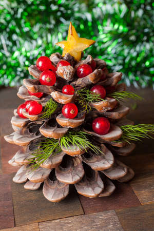 Pine cone decorated with cranberries as tree for christmas, surrounded with green Christmas garlandの写真素材