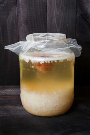 Fermented water kefir with grains on the bottom of jar and a floating piece of dry fruits