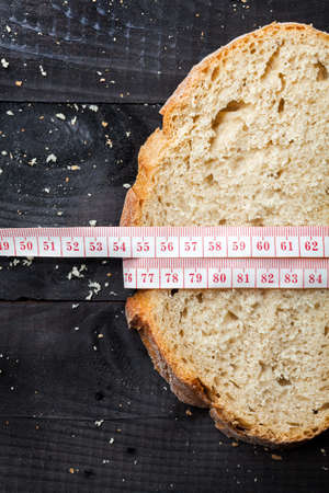 Bread slices on black wooden table with tape measure 