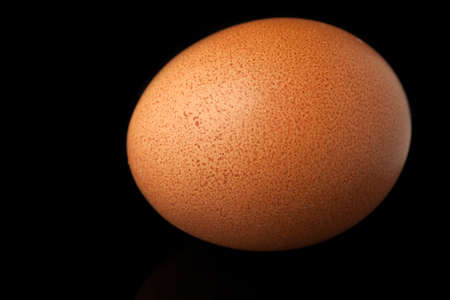 Brown egg isolated over black backgroundの写真素材