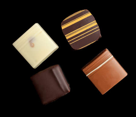 An assortment of fine chocolates in white, dark, and milk chocolate on black backgroundの写真素材