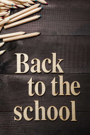 Letters Forming the Words ''Back to School'' with a few color pencils on dark wooden backgroundの写真素材